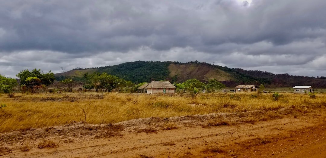 a dirt road in front of a grassy hill
