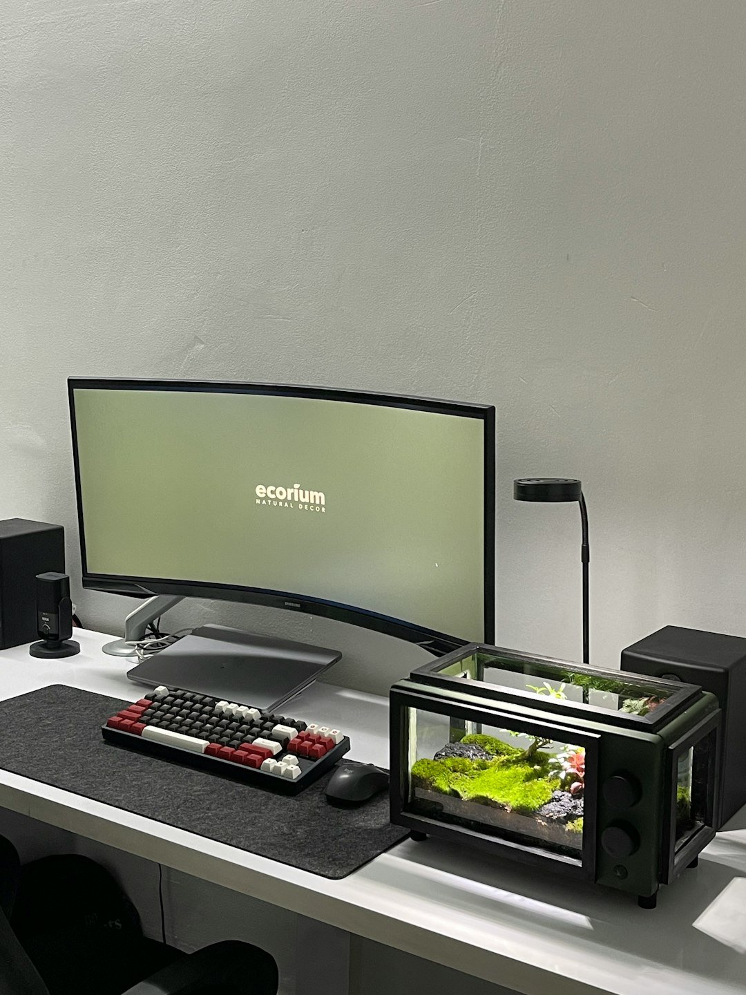 a desk with a monitor, keyboard and a remote control