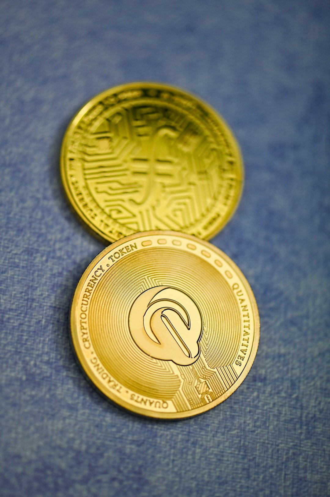 two gold coin sitting on top of a blue surface