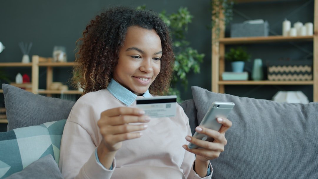 Young woman holding credit card and smartphone.