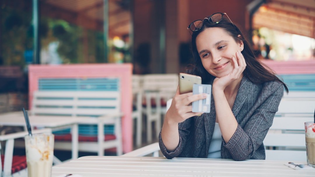 Woman smiling while looking at her phone at a cafe.