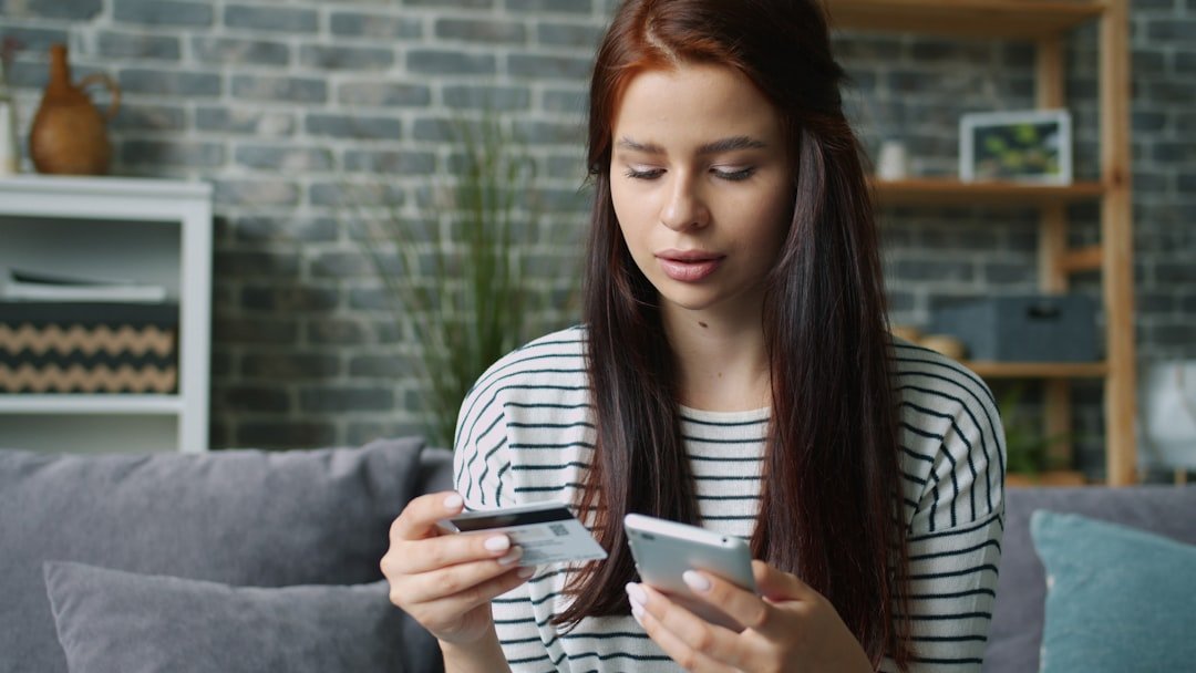 Woman holding credit card and smartphone for online shopping.