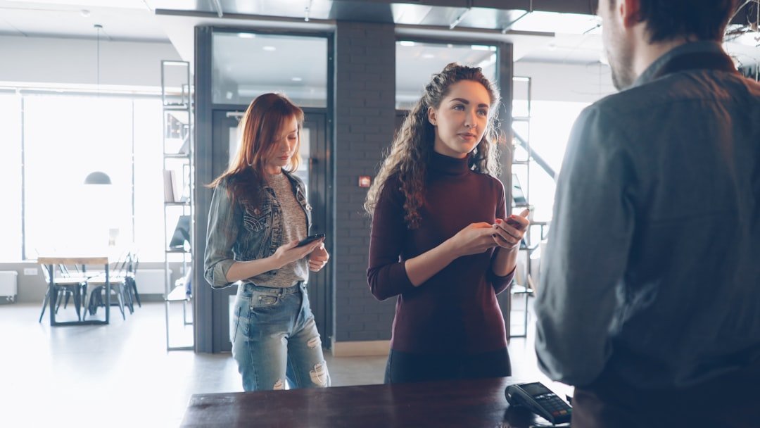 Two women and a man engage at a counter.